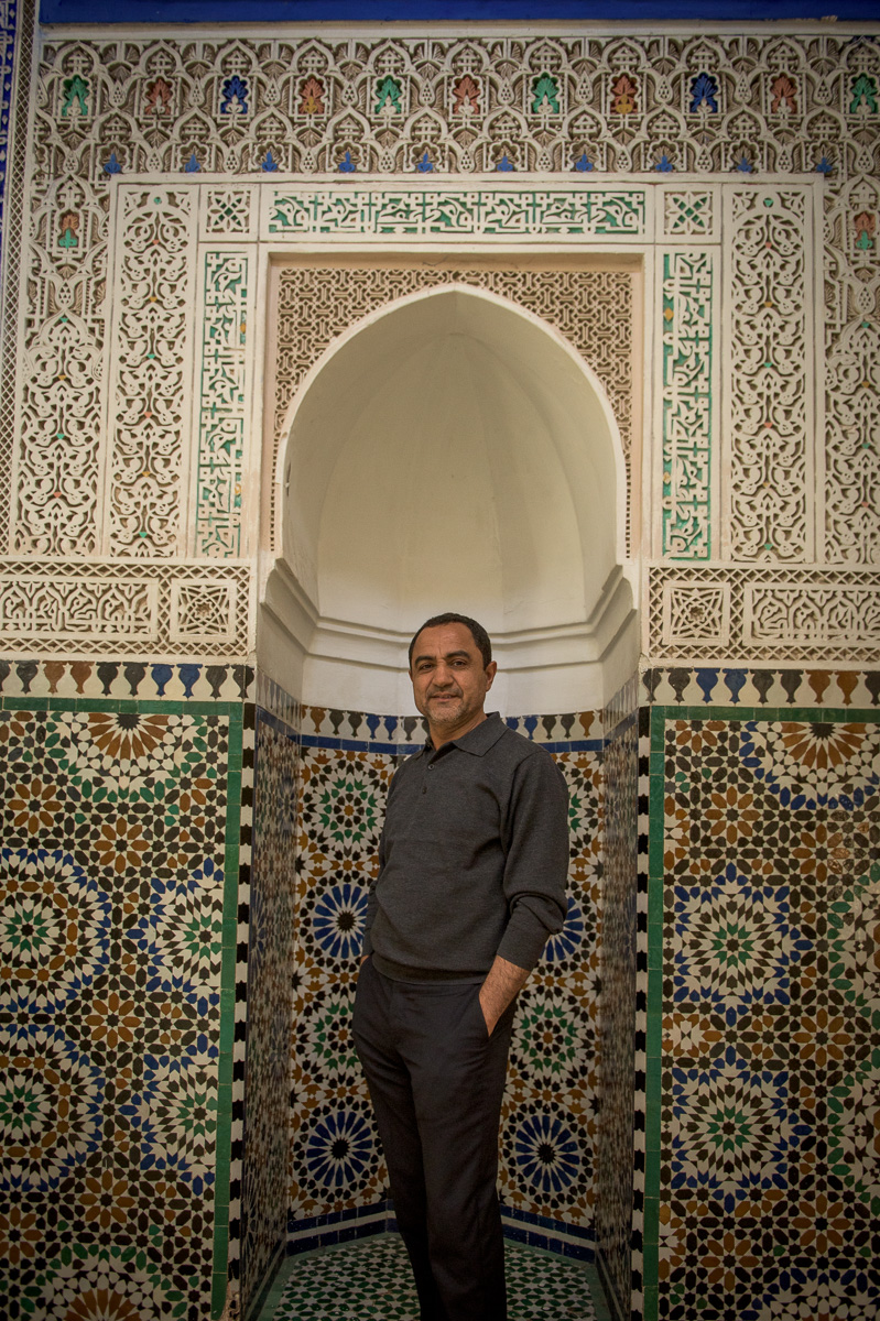 Mohamed poses in front of a niche incorporating many elements of classic Moroccan Islamic design.